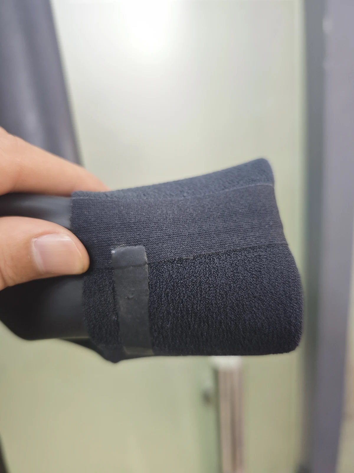 A folded black cuff showing inner fabric and joining strip. Detail of the INSEAKU minimal black back zip triathlon wetsuit.