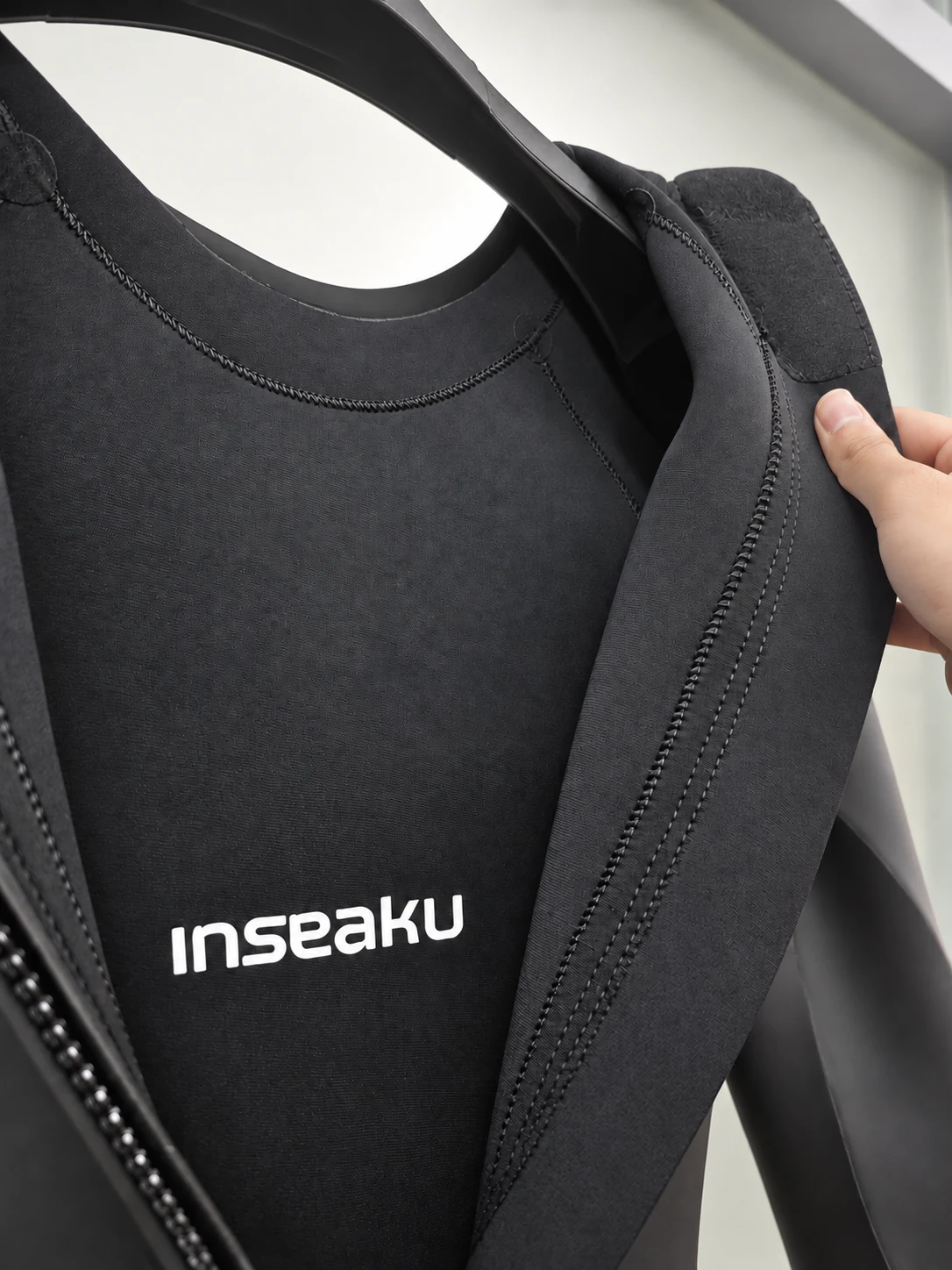 Inner neck lining and rear zipper edges. Detail of the INSEAKU minimal black back zip triathlon wetsuit.