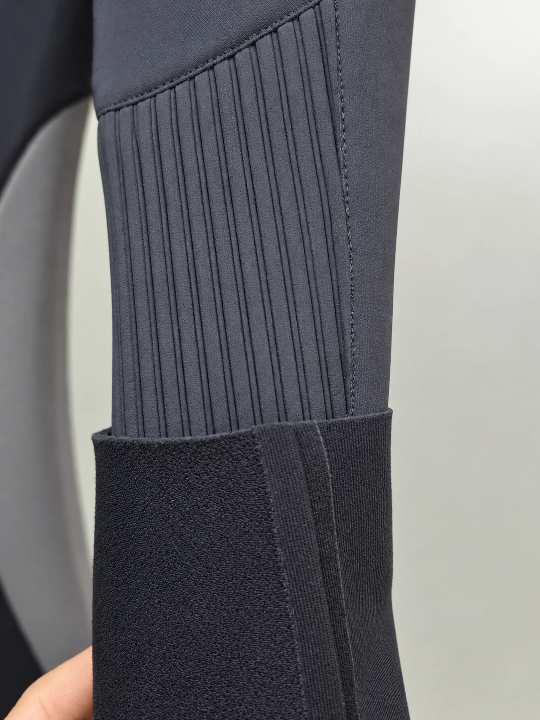 A folded cuff and ribbed forearm panel. Detail of the INSEAKU orange chevron triathlon wetsuit.