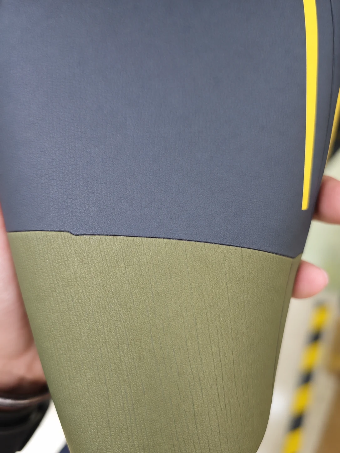 A cuff panel meeting a contrasting fabric section. Detail of the INSEAKU yellow outline triathlon wetsuit.