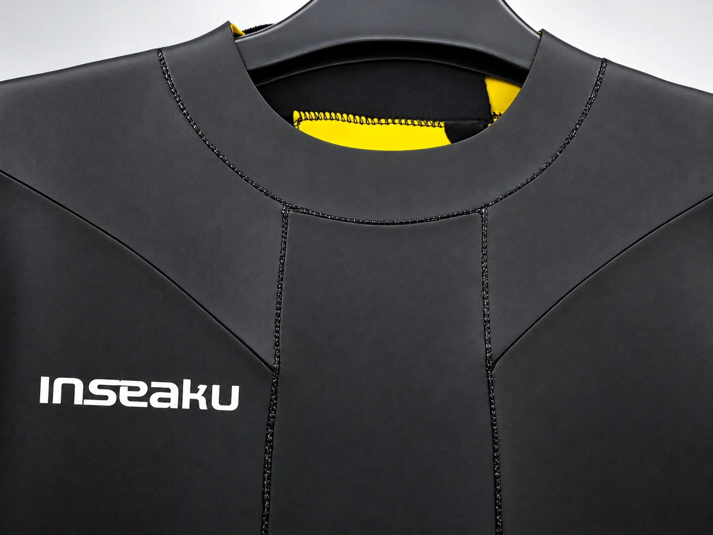 Front neckline and curved chest panel seams. Detail of the INSEAKU yellow stripe triathlon wetsuit.