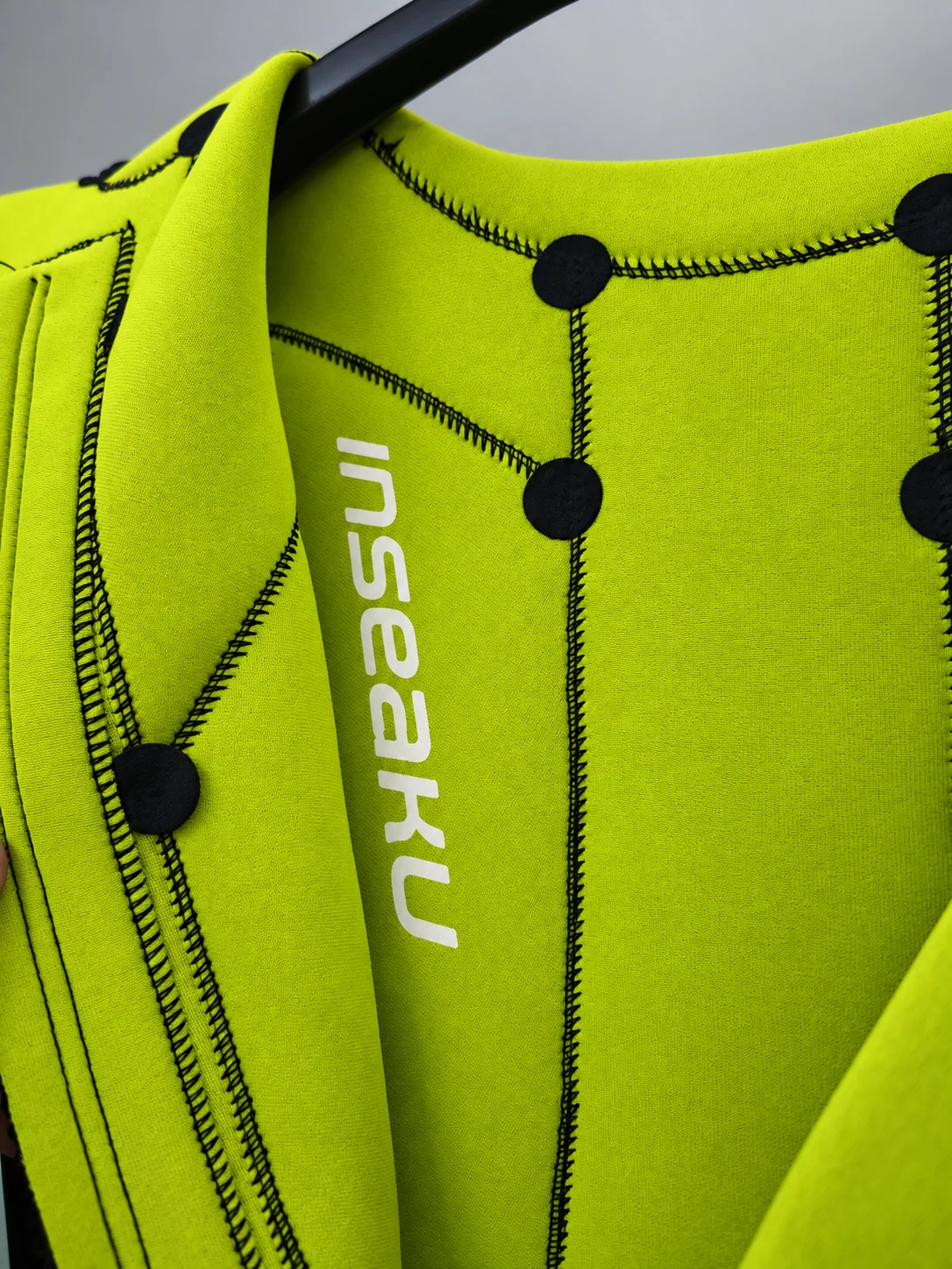 Yellow inner lining with black seams and circular reinforcement patches. Detail of the INSEAKU yellow stripe triathlon wetsuit.